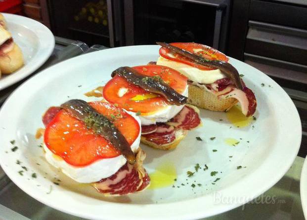 Tapa de jamón ibérico con queso panela, una rodajita de tomate y anchoas